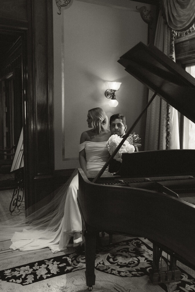Bride and groom sit at piano in historic wedding venue in Minneapolis, Minnesota