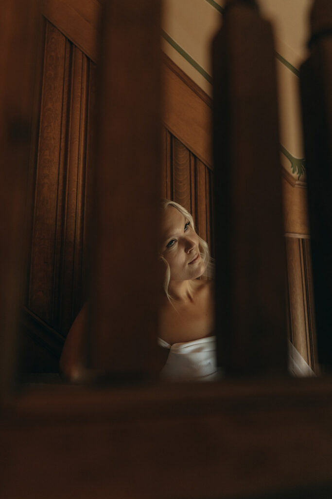 Elegant bride captured through the staircase rungs at Van Dusen Mansion
