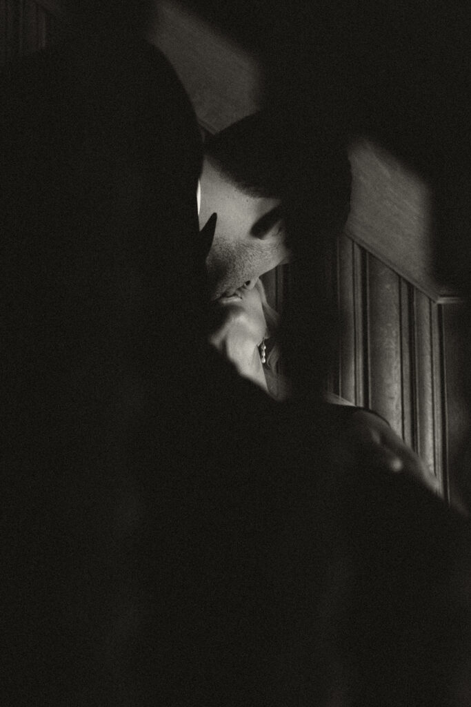 Dramatic portrait of bride and groom kissing on staircase of historic wedding venue