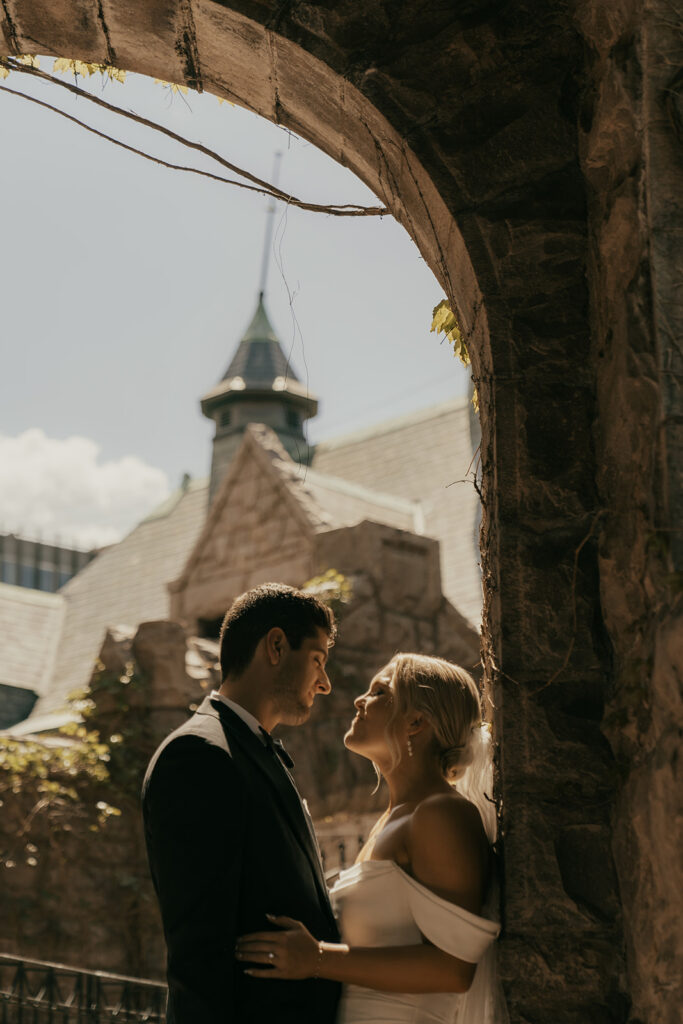 Bride and groom lock eyes in stone archway of Van Dusen Mansion in Minneapolis, Minnesota