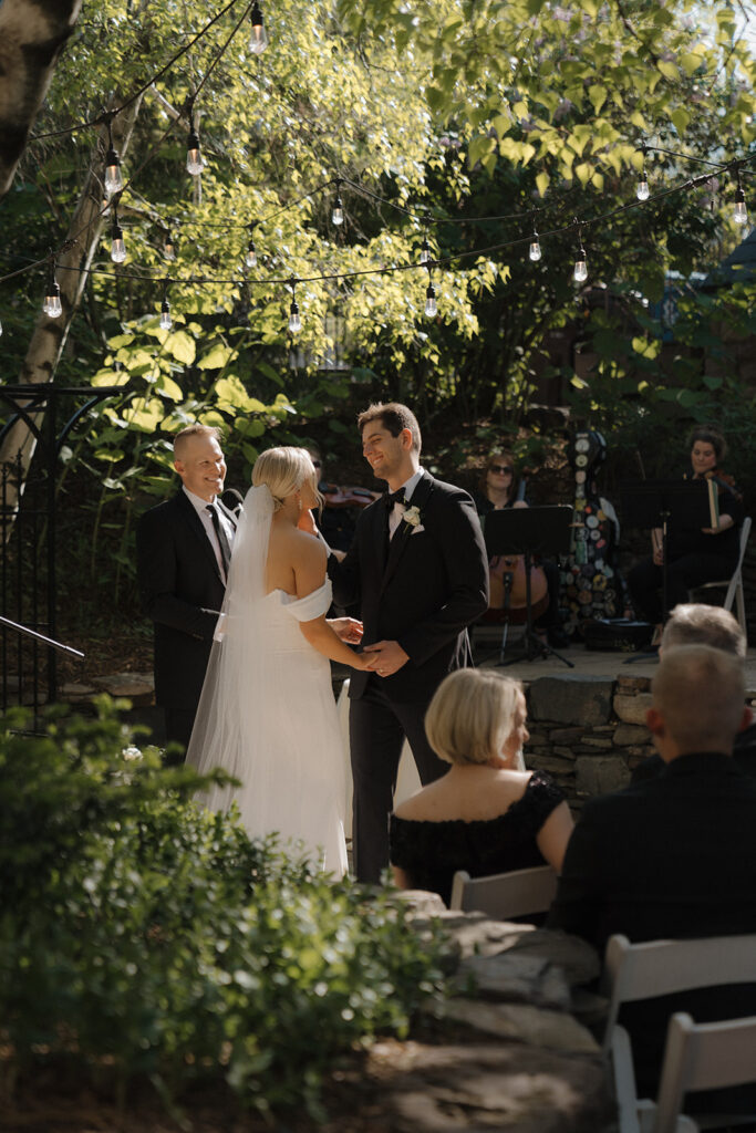 Bride and groom exchange vows in light-filled courtyard at historic wedding venue Van Dusen Mansion